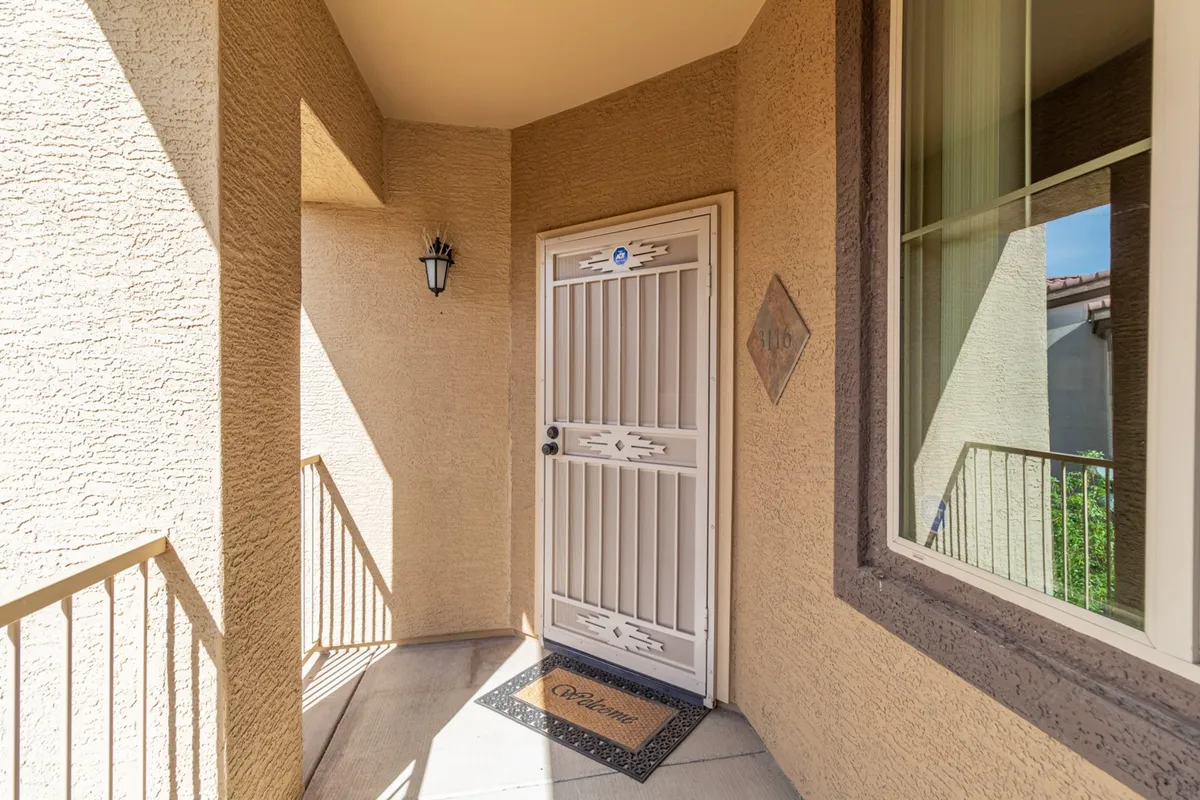 A welcoming entrance scene, showcasing the front door, a welcome mat, and a light fixture, with a glimpse of the corner wall. The mood is inviting, suggesting hospitality and the first impression guests receive upon arrival.