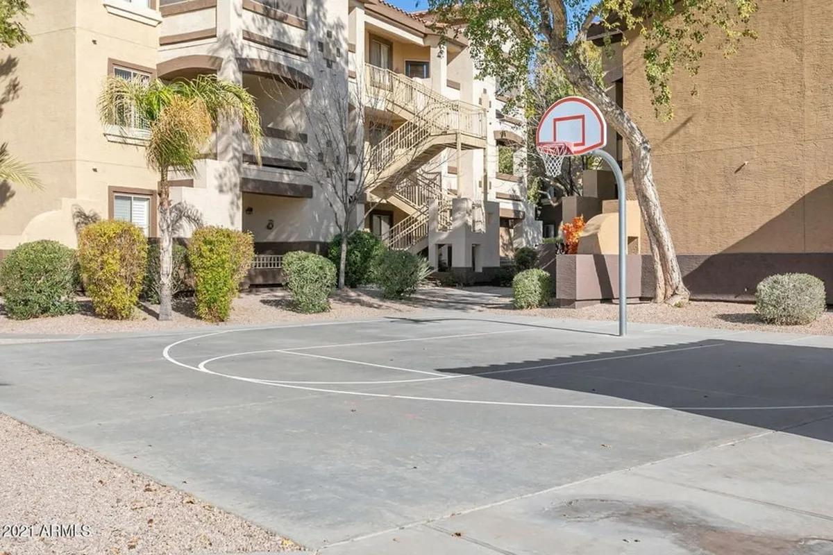 This exterior image features a basketball hoop set in a courtyard bordered by greenery. This active scene emphasizes the outdoor recreational amenities available to guests, reinforcing the theme of group activities and friendly competition.