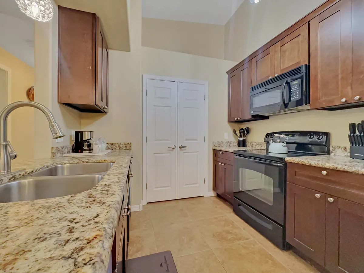A warm, welcoming kitchen with granite countertops, modern appliances, and dark cabinetry. The area is spacious and set up for cooking, entertaining, and family gatherings, highlighting the functionality required for extended stays.
