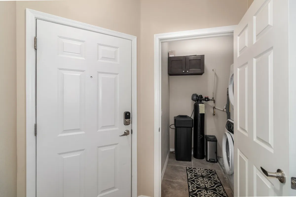 A functional laundry area featuring laundry appliances, a storage cabinet, and a view toward the front door. The space is clean, tidy, and ready for everyday life, underscoring the ease of long-term living.
